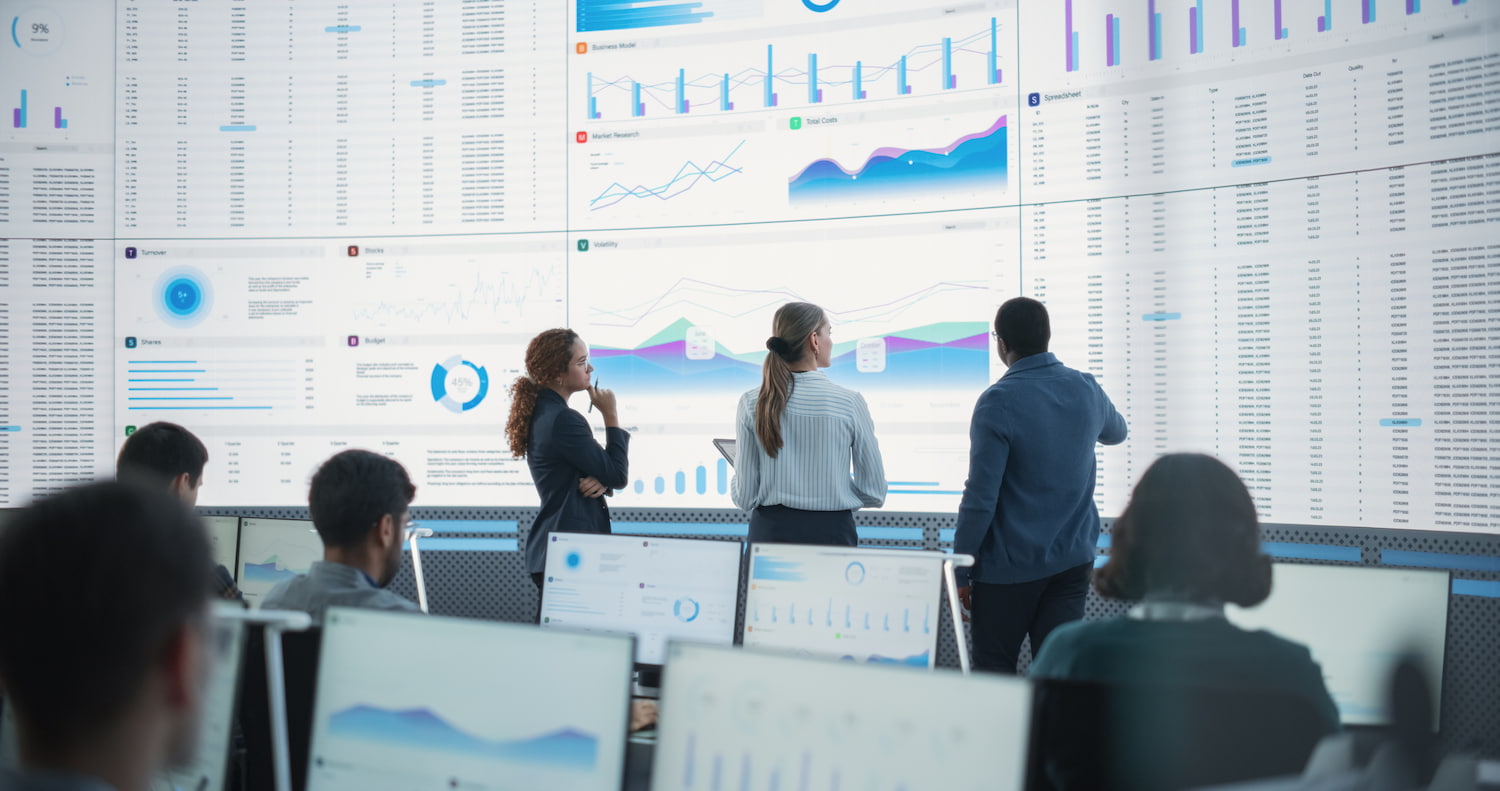Analysts looking at a data dashboard wall.